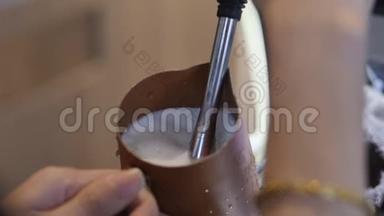 专业咖啡师。 制作新鲜的磨碎咖啡，咖啡师在制作过程中将牛奶倒入杯子